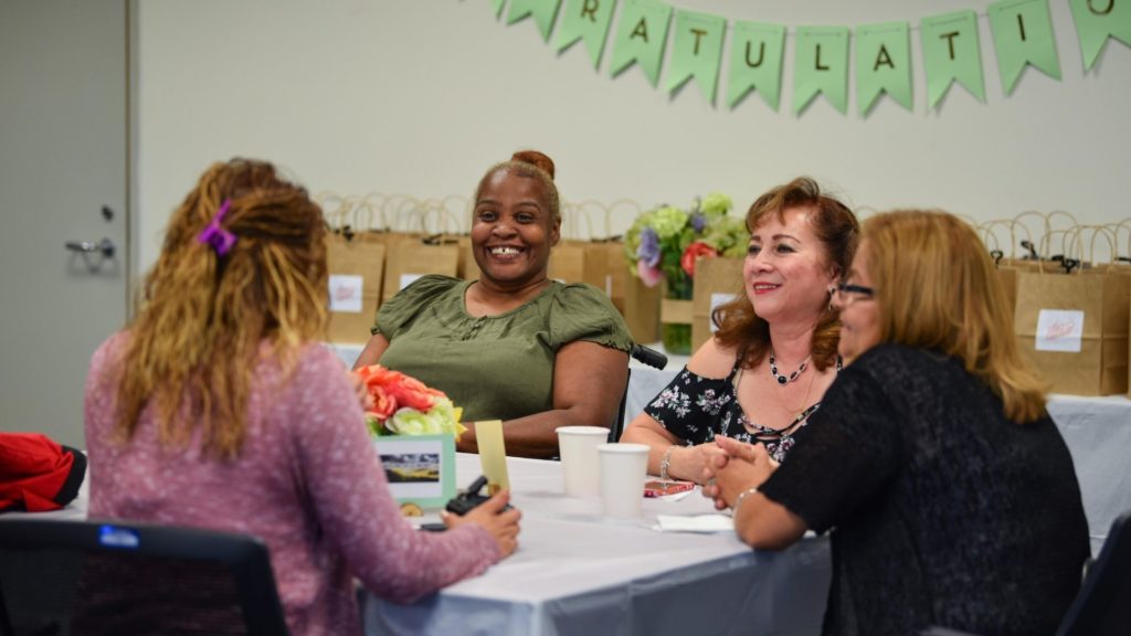 Four adults laughing and sitting around a table.