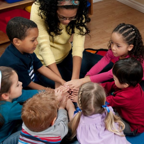 Children and teacher with hands in circle