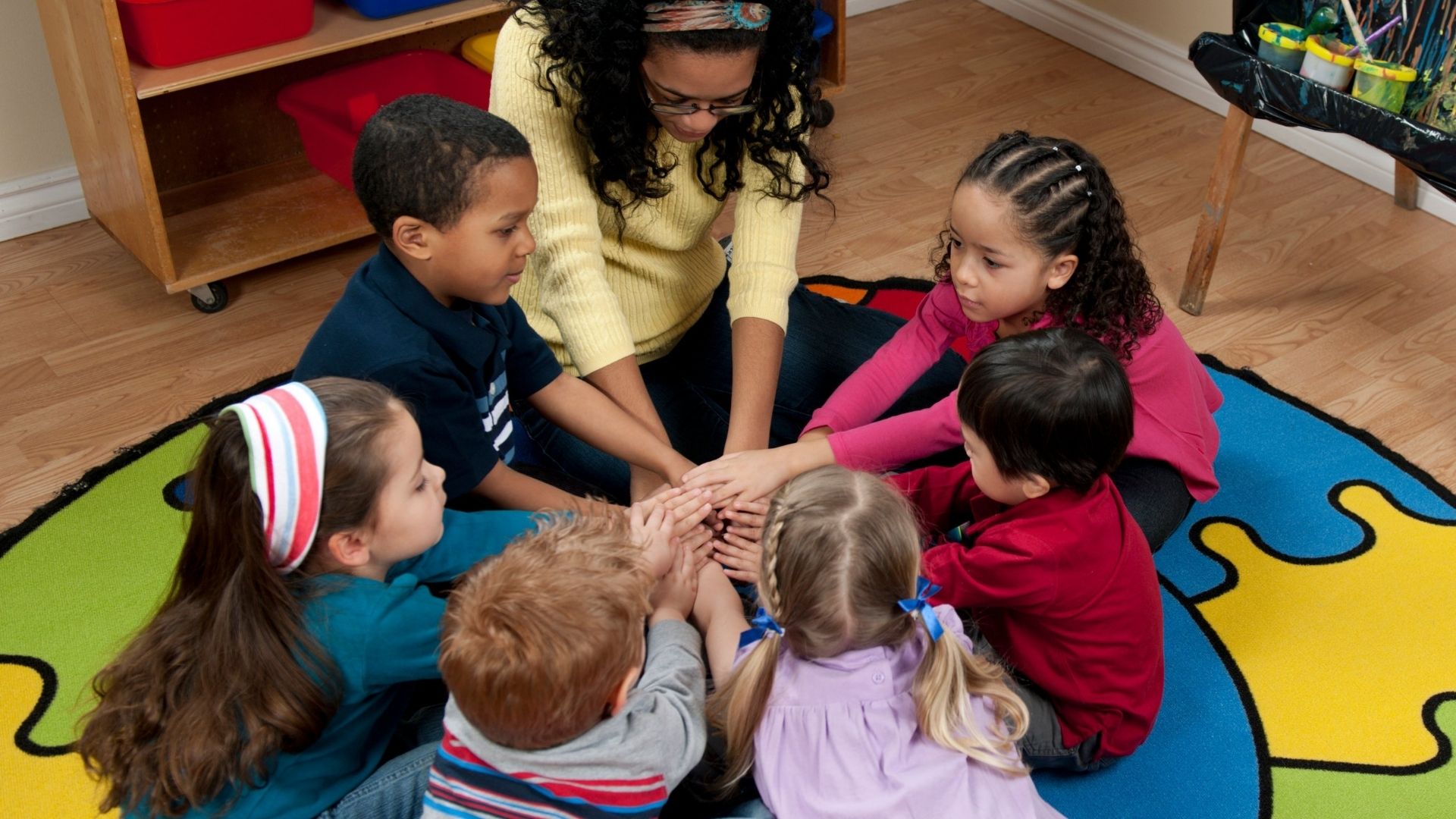 Children and teacher with hands in circle