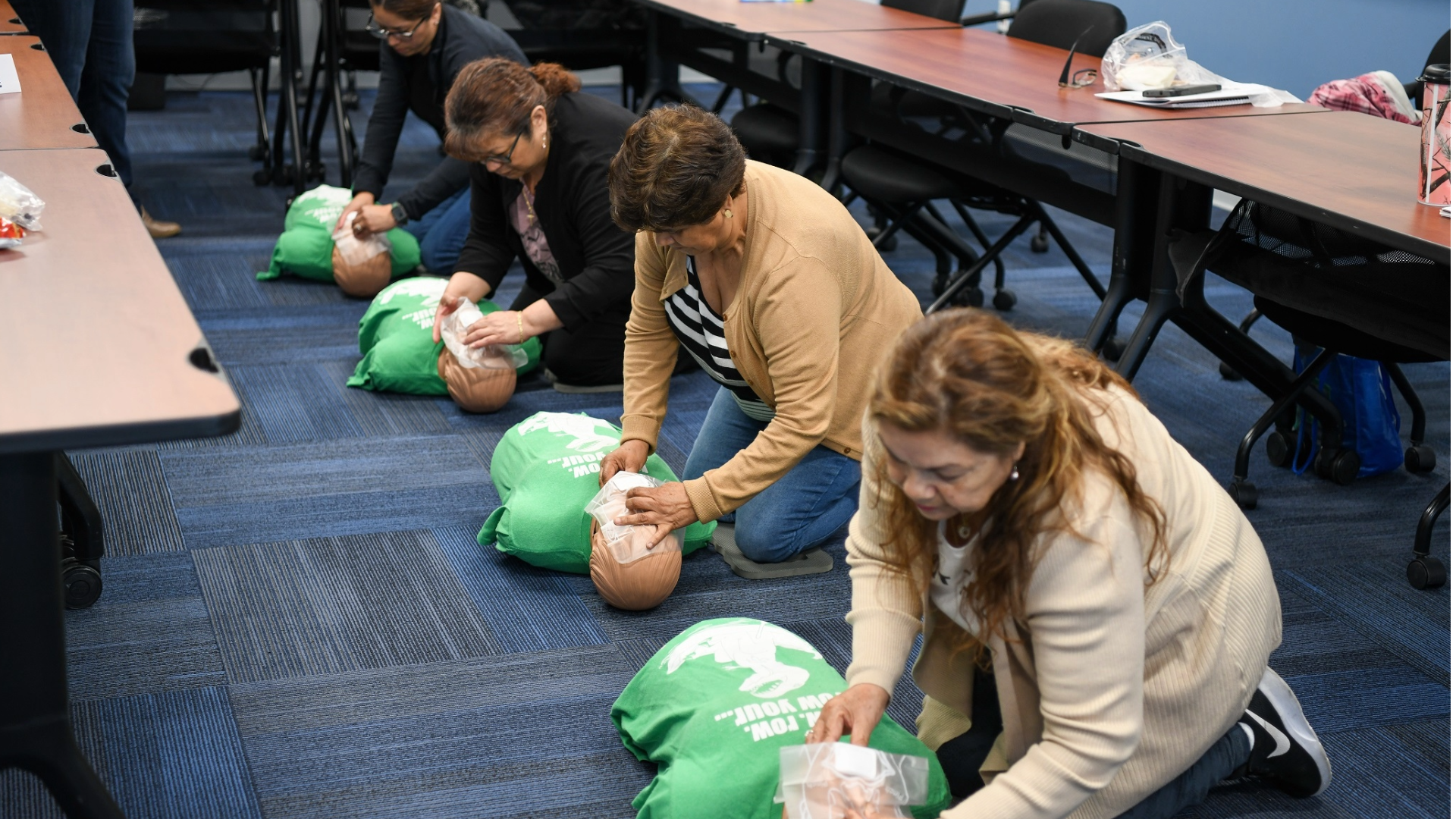 Four adults performing CPR on a dummy during a training.