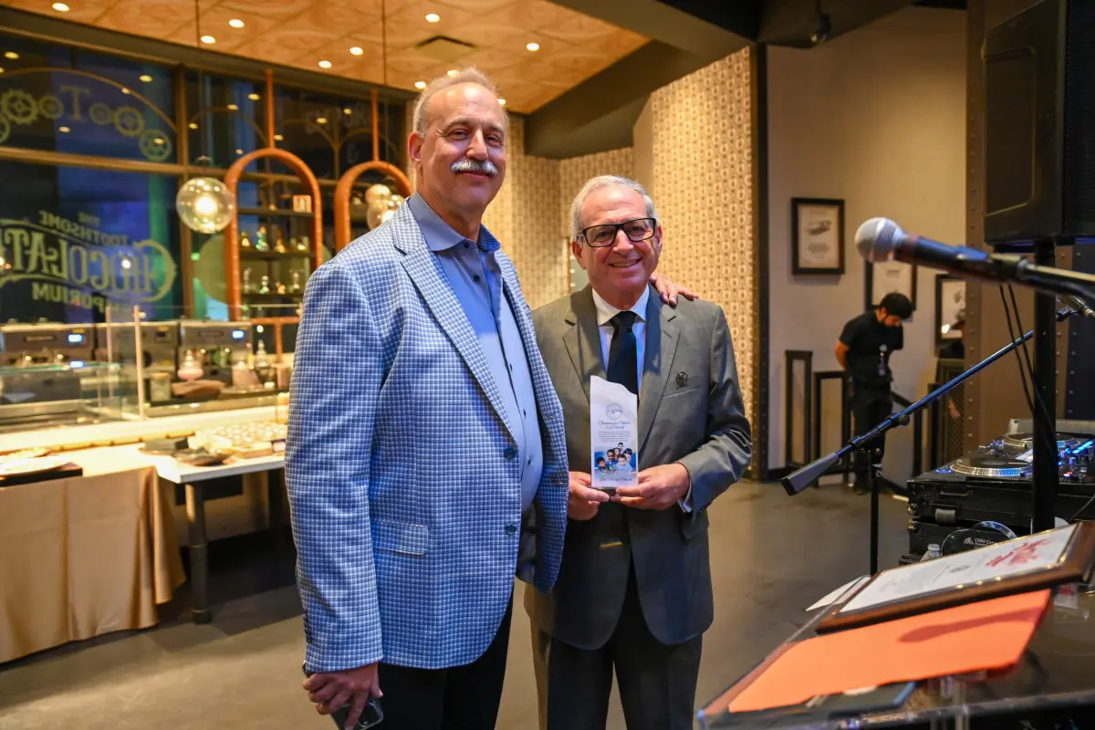 Adrian Stern and Dr. Michael Olenick smiling as Dr. Michael Olenick holds an award