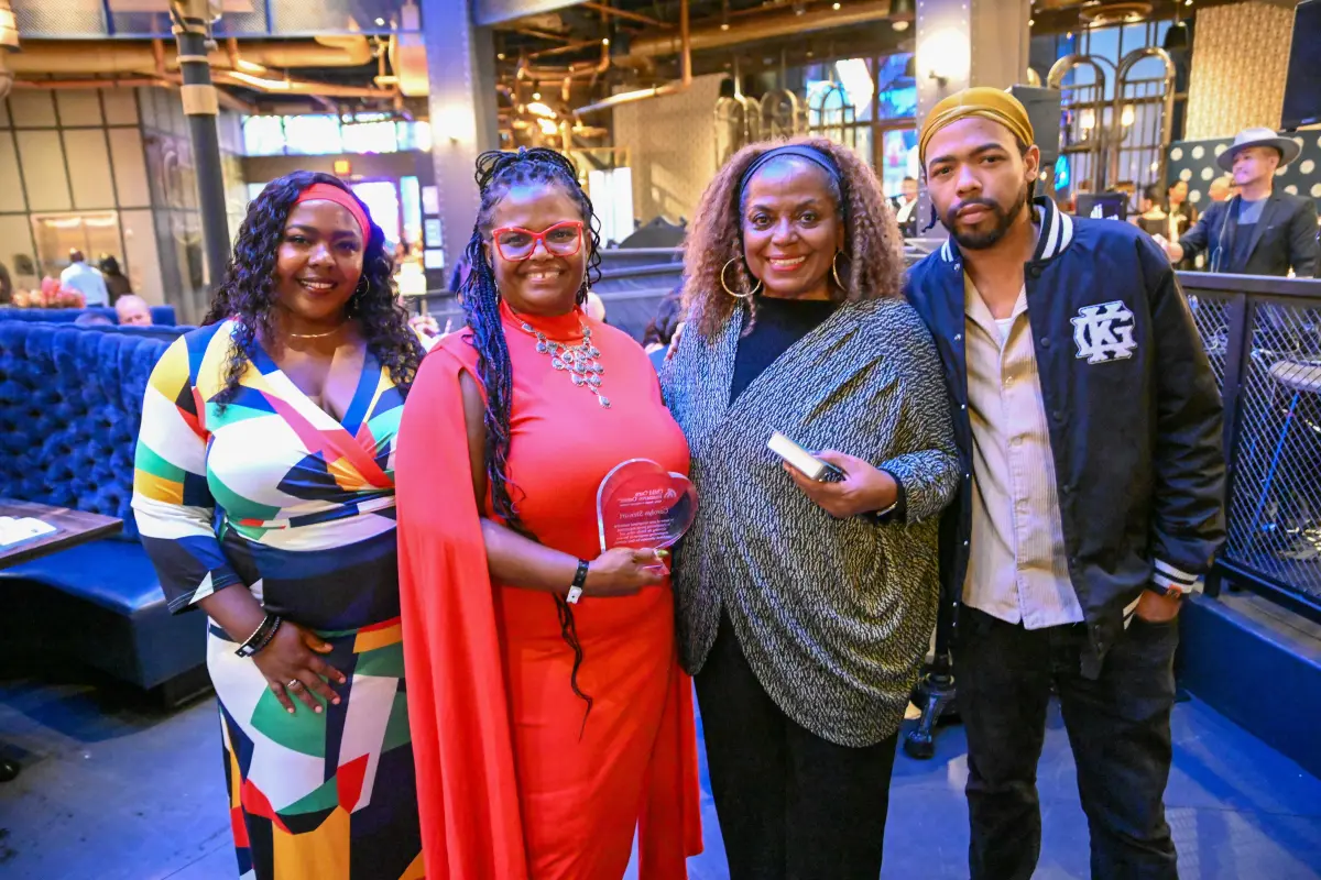 Carolyn Stewart in a red dress with 3 other guests grouped together and smiling inside the The Toothsome Chocolate Emporium & Savory Feast Kitchen